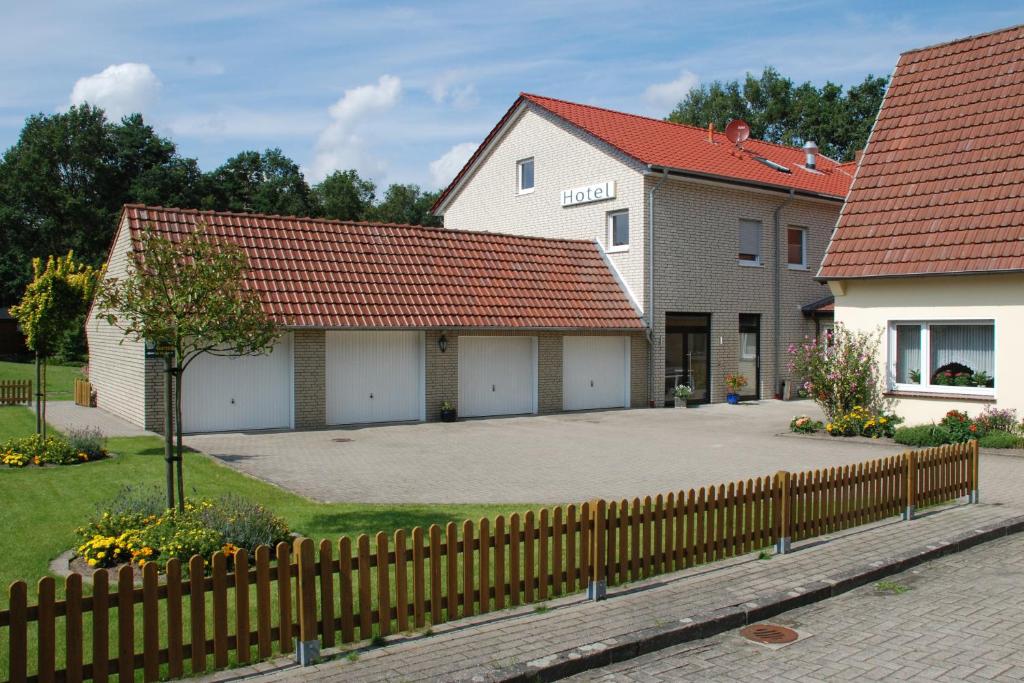 deux bâtiments avec des toits rouges et une clôture dans l'établissement Gasthaus-Witte, à Wallenhorst