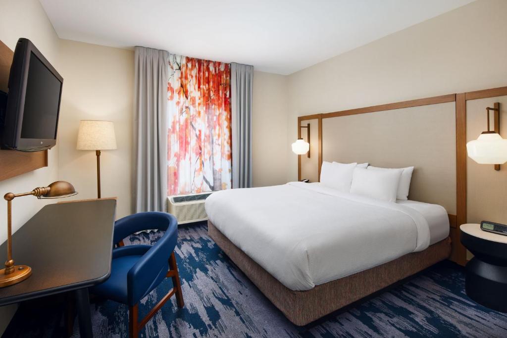 Fairfield Inn & Suites Worcester Auburn في أوبورن: غرفة فندقية فيها سرير ومكتب وتلفزيون