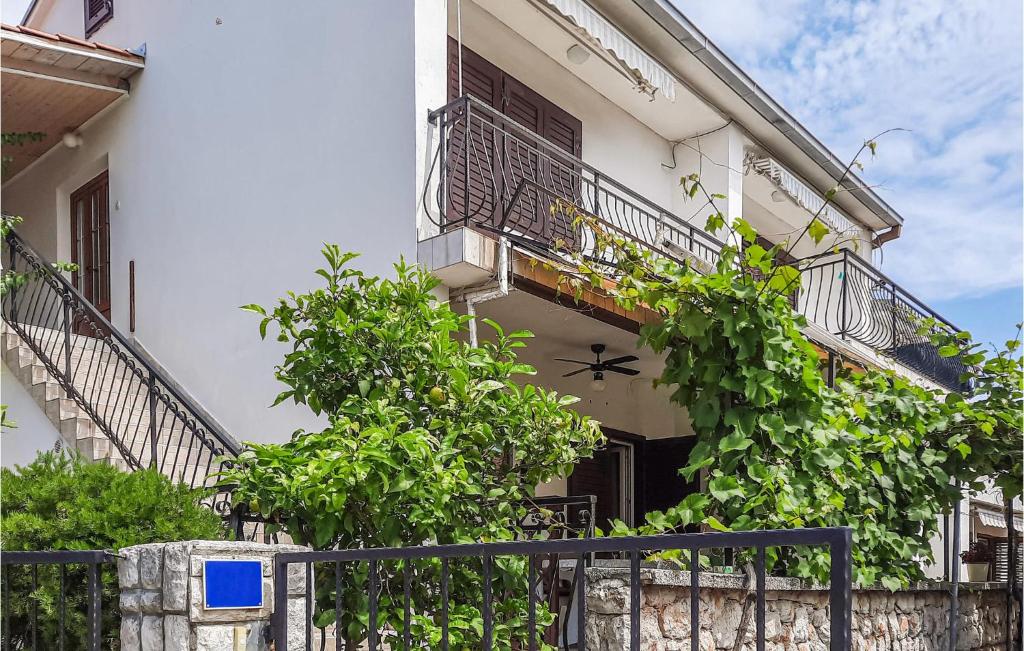 a white building with balconies and trees and a fence at Beautiful Apartment In Mali Losinj With Kitchen in Mali Lošinj