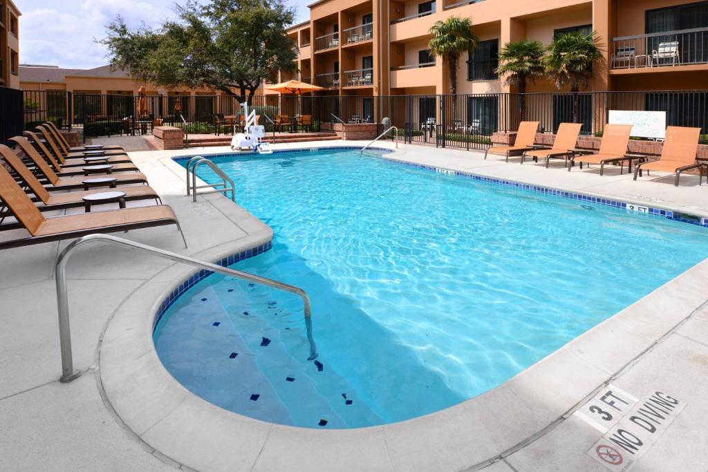 a large swimming pool with chairs and a building at Courtyard by Marriott San Antonio Medical Center in San Antonio