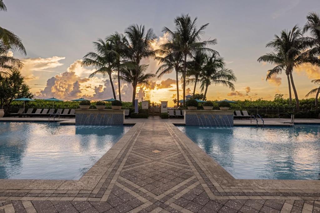 une piscine avec des palmiers et un coucher de soleil en arrière-plan dans l'établissement Marriott's Oceana Palms, à Palm Beach Shores