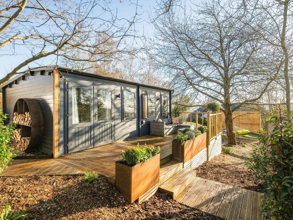 a tiny house with a deck in a garden at The Cosy Cabin in Clapton in Gordano