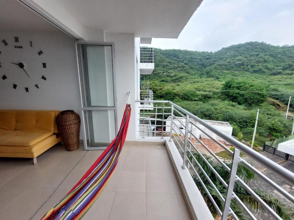 d'un balcon avec un canapé et un réveil sur le mur. dans l'établissement Apartamento Aqualina Orange Piso 5 Vista a Montañas 2 Habitaciones, à Girardot