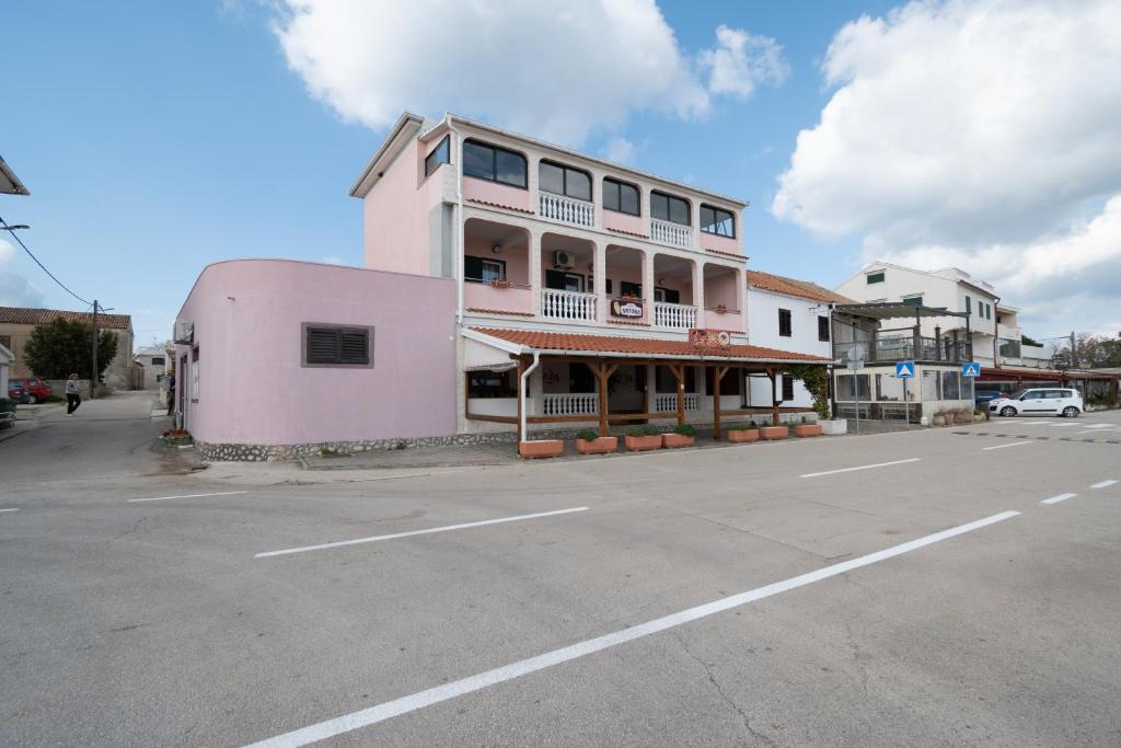 różowy budynek po stronie ulicy w obiekcie Apartments by the sea Pasman - 8221 w mieście Pašman