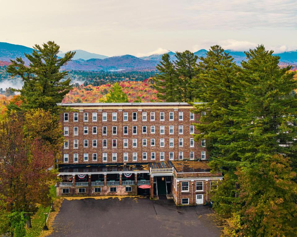 a large brick building in the middle of trees at The Pines Inn in Lake Placid
