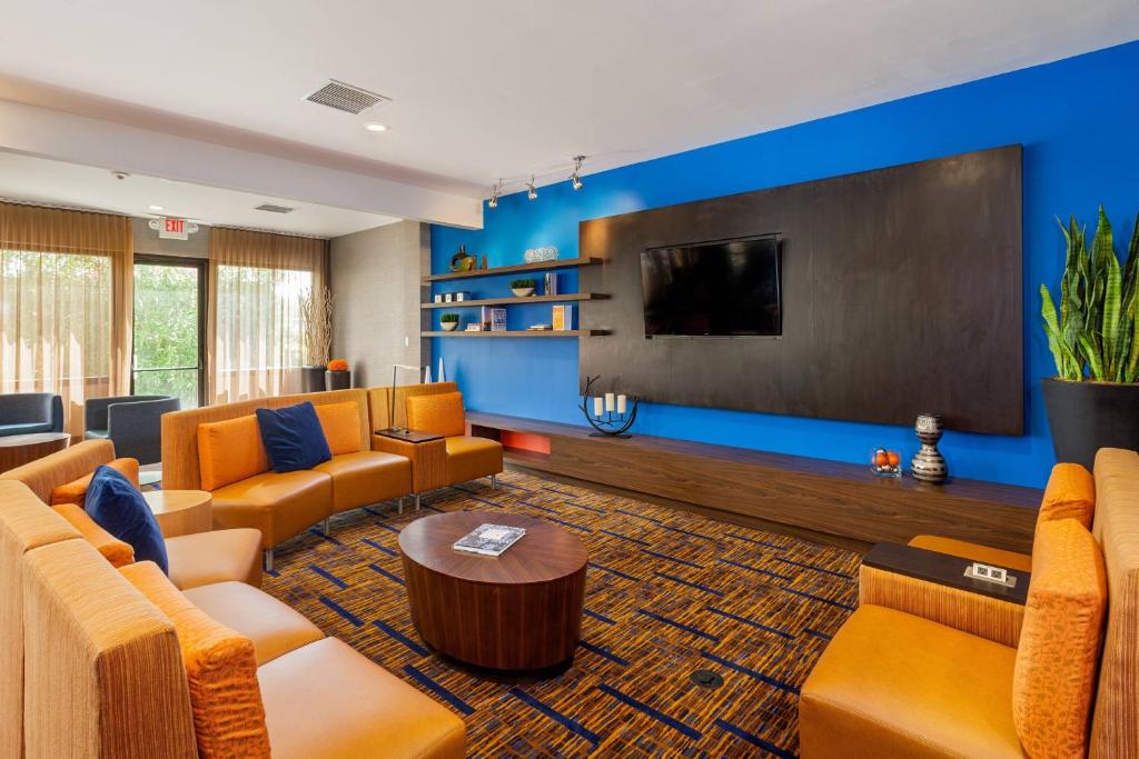 una gran sala de estar con sofás naranjas y TV de pantalla plana. en Courtyard Fairfield Napa Valley Area, en Fairfield