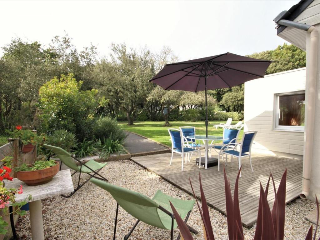 eine Terrasse mit Tisch und Stühlen und einem Sonnenschirm in der Unterkunft Gîte verdoyant proche plages avec terrasse privative, idéal famille - La Turballe - FR-1-306-968 in La Turballe