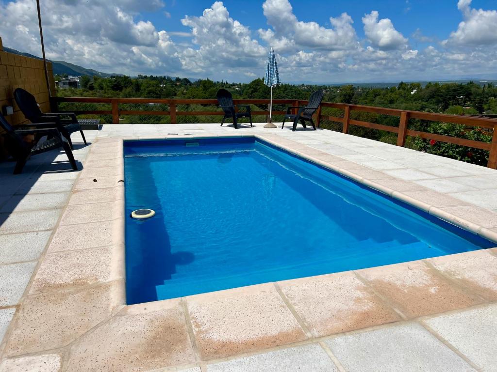 una piscina en un patio con 2 sillas en Palotes Sierras Apart en Villa Giardino