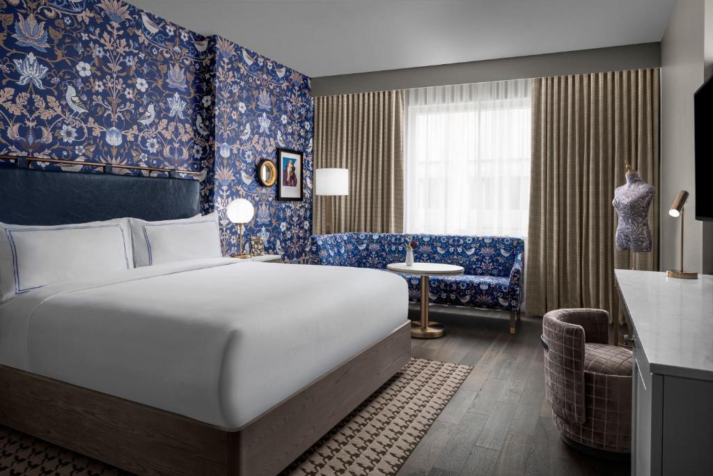 um quarto de hotel com uma cama grande e uma cadeira em The Dorian, Autograph Collection em Calgary