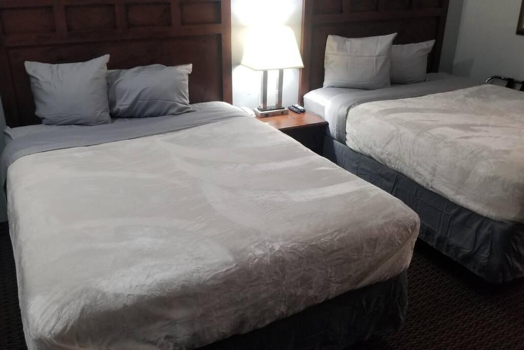 een hotelkamer met 2 bedden en een tafel met een lamp bij OSU 2 Queen Beds Hotel Room 136 Wi-Fi Hot Tub Booking in Stillwater
