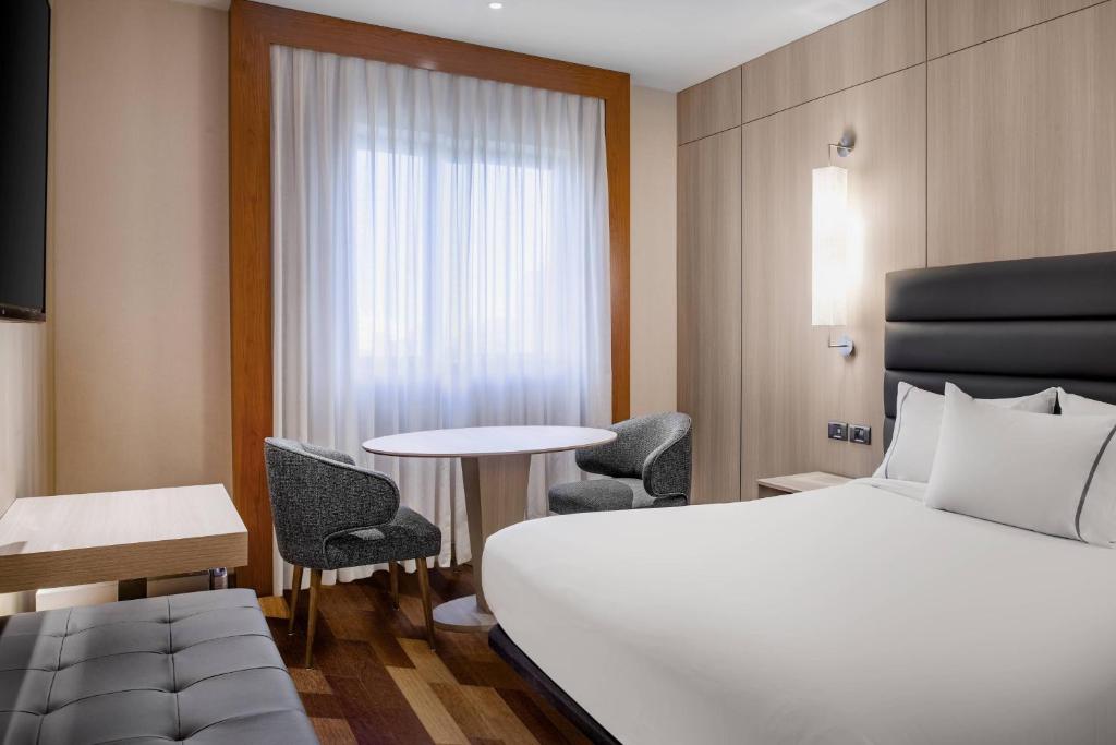 タラゴナにあるAC Hotel Tarragona by Marriottのベッド、テーブル、椅子が備わるホテルルームです。