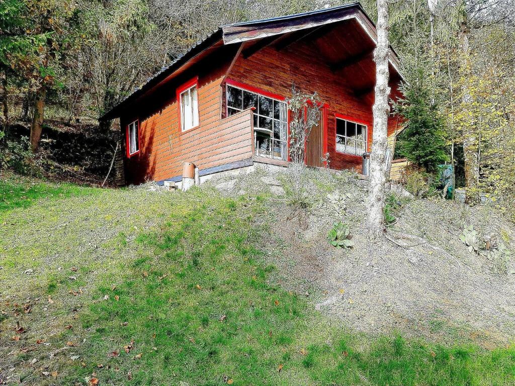 una pequeña casa roja al lado de una colina en Cozy Chalet in La Roche-en-Ardenneon Belgium with Terrace, en Bertogne