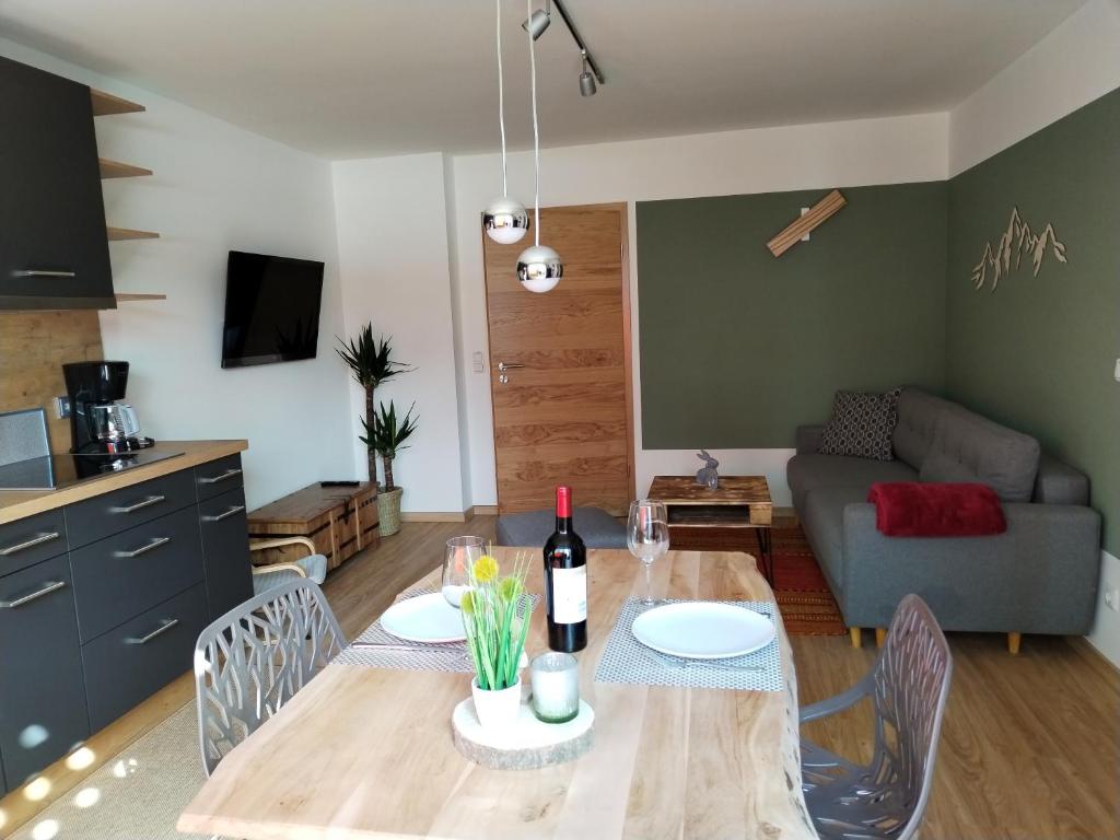 ein Wohnzimmer mit einem Tisch und einer Flasche Wein in der Unterkunft Ferienwohnung am Gänsbach in Grassau