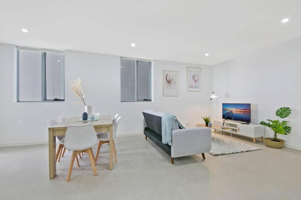 a living room with a table and a couch and chairs at Aircabin｜Mascot｜Spacious & Modern｜Walk to station in Sydney