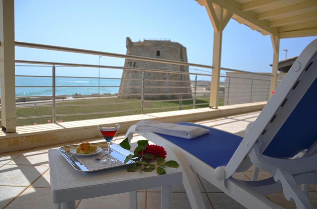 un tavolo con un bicchiere di vino sul balcone con castello di Hotel Teti a Torre Mozza