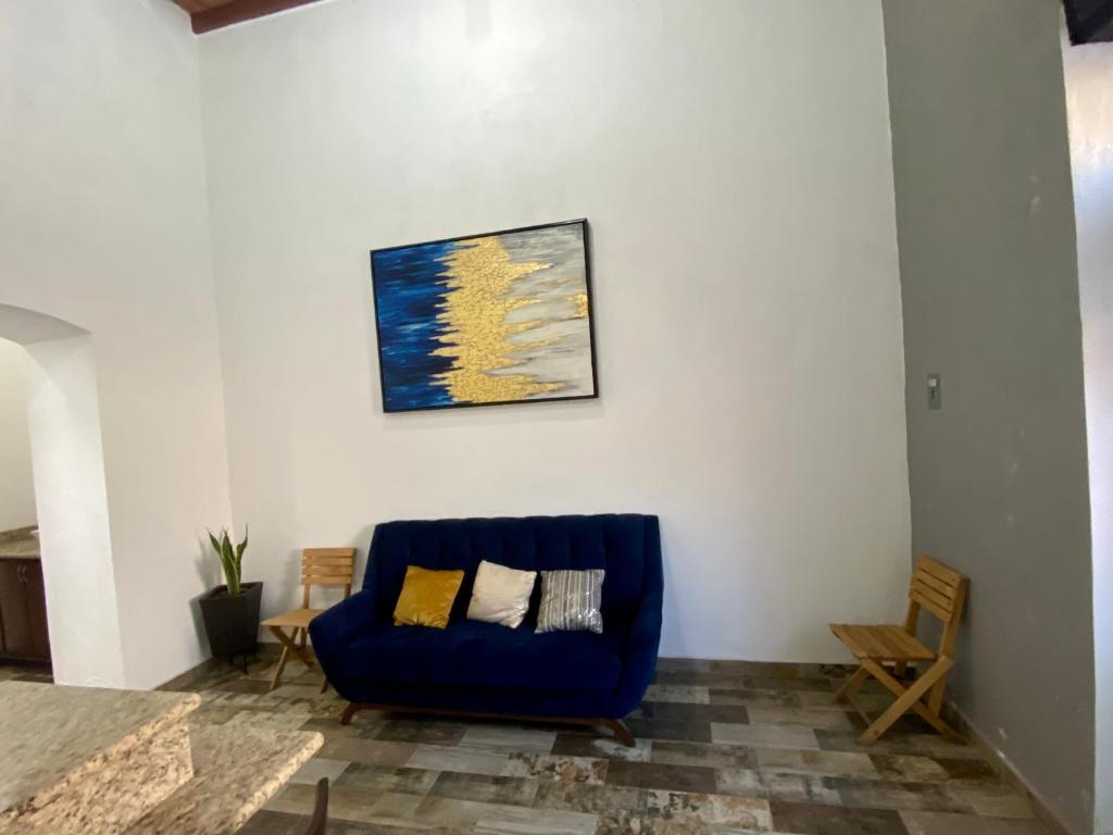 un divano blu in soggiorno con un dipinto sul muro di Departamento Frente a la Plaza Principal Jala a Jala