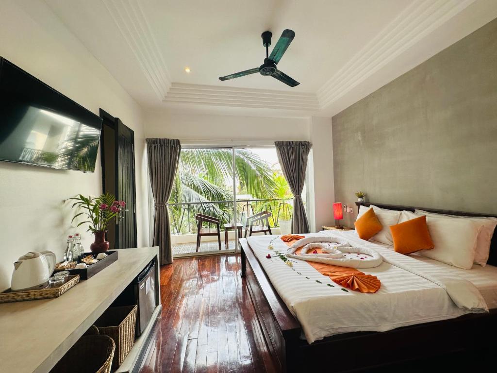 a bedroom with a large bed with a ceiling fan at Boutique Indochine d'Angkor in Siem Reap