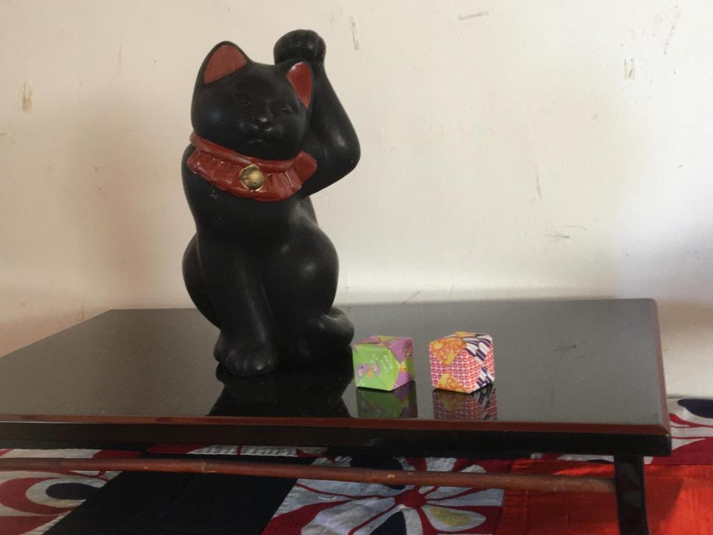 una estatua de gato negro sentada sobre una mesa en MOMO HOUSE, en Inami