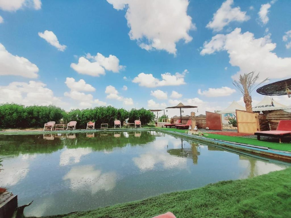 a pool of water with chairs and clouds in the sky at استارز كامب in Bawiti