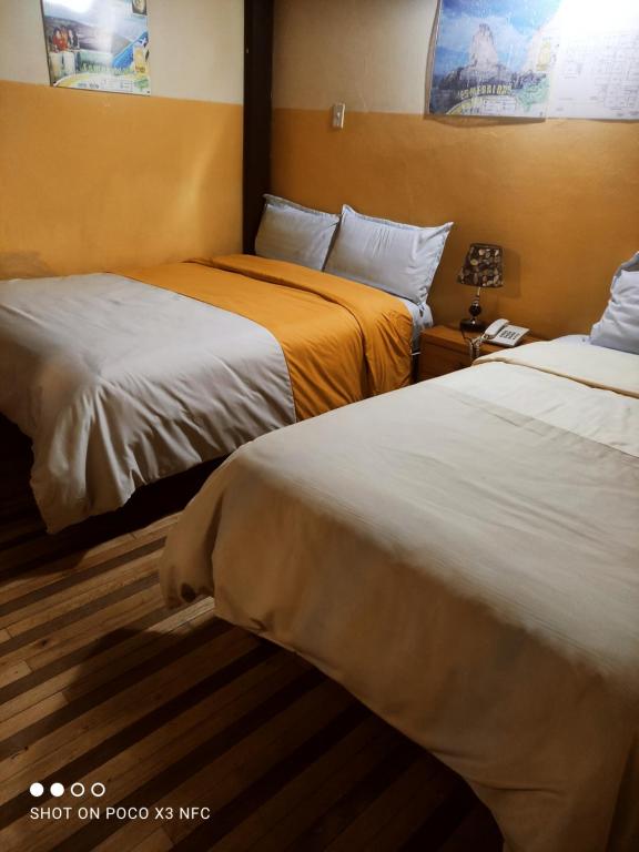 Habitación de hotel con 2 camas y teléfono en Hostal puerta del sol en Quito