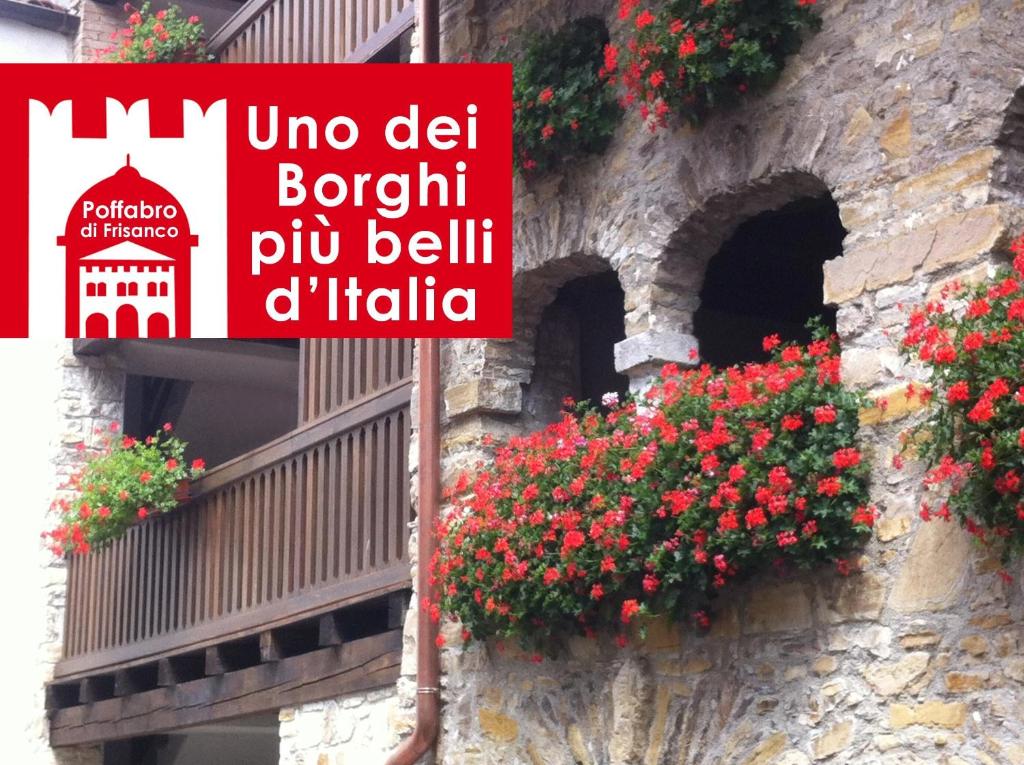 a sign on a building with flowers in a window at Nonna Leni - Rooms & Apartments in Frisanco