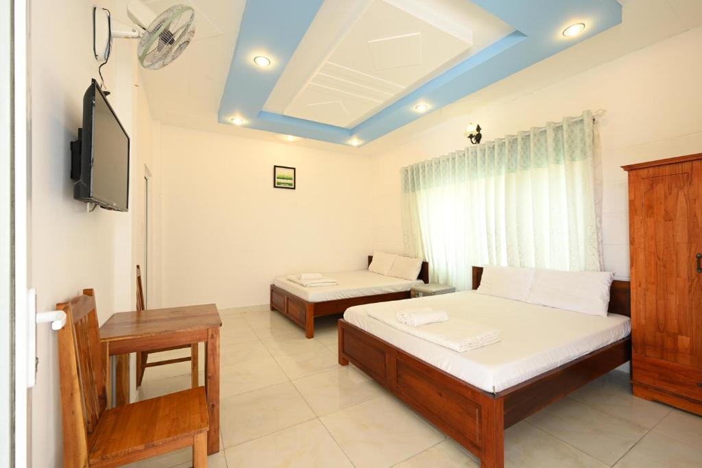 Habitación con 2 camas y TV. en ALOHA HOTEL SUỐI MÂY PHÚ QUỐC, en Phu Quoc