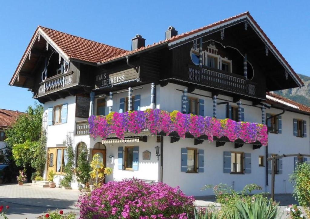 un edificio blanco con flores púrpuras. en Haus Edelweiß, en Unterwossen