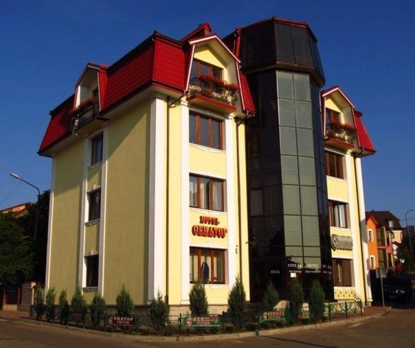 a large white building with a red roof at Hotel&Restaurant SENATOR in Truskavets