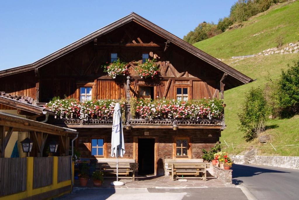 ein Holzhaus mit Blumen auf dem Balkon in der Unterkunft Gasthof Mühle in Wattens