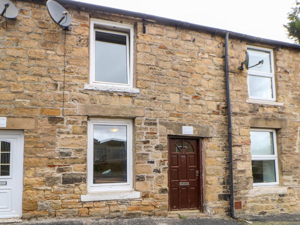 a brick building with a brown door and windows at Hunter Cottage in Haltwhistle