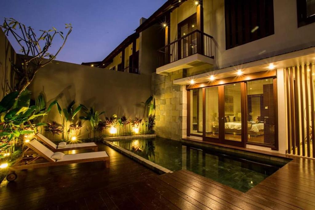 a house with a swimming pool in front of a building at Tolgay Living Villas in Seminyak