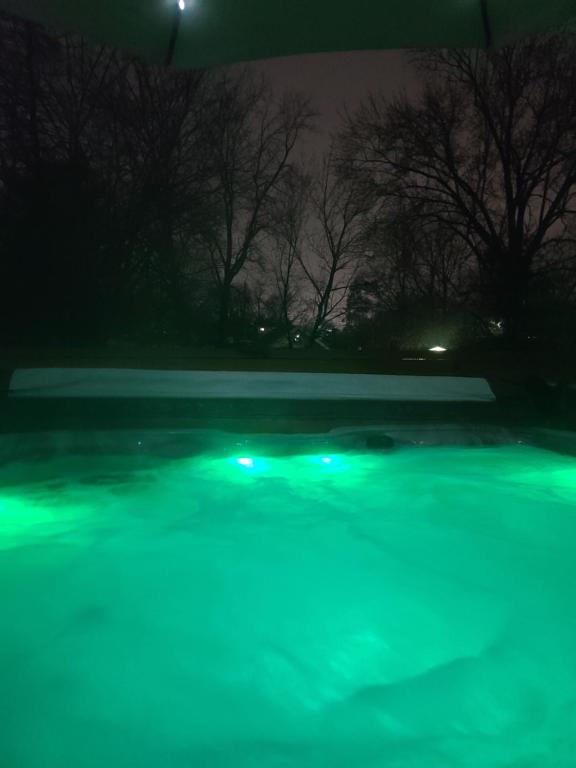 - Vistas nocturnas a una piscina con luces verdes en Outdoor Hot Tub and Cozy King Bed en Lansing