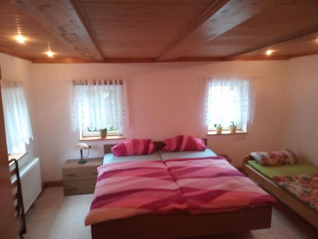 Schlafzimmer mit einem Bett mit rosa Bettwäsche und Fenstern in der Unterkunft Ferienwohnung zum Sebnitzer Hirsch in Sebnitz