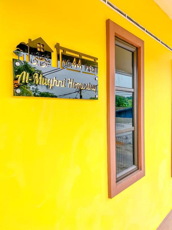 un edificio amarillo con un cartel en el costado en Al-Mughni Homestay en Pasir Gudang