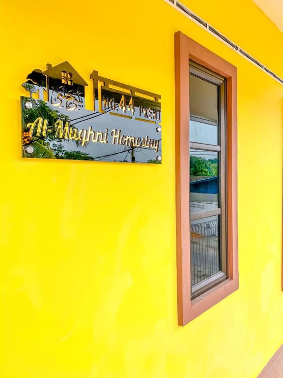 a yellow building with a sign on the side of it at Al-Mughni Homestay in Pasir Gudang