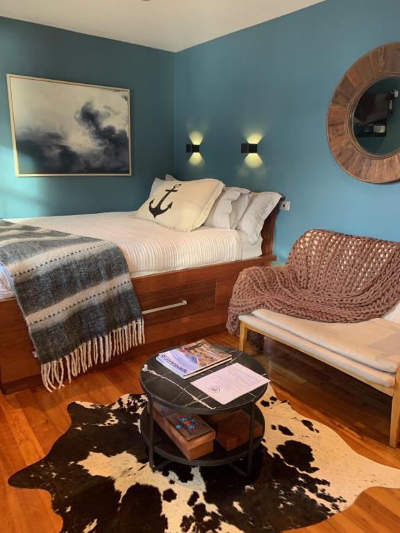 een slaapkamer met een bed, een bank en een stoel bij Salt Box Hideaway in Strahan