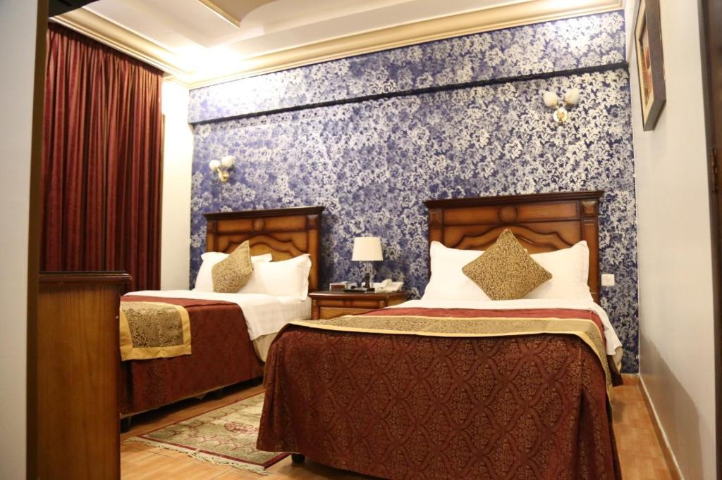 1 dormitorio con 2 camas y pared azul en Abha Hotel, en Abha