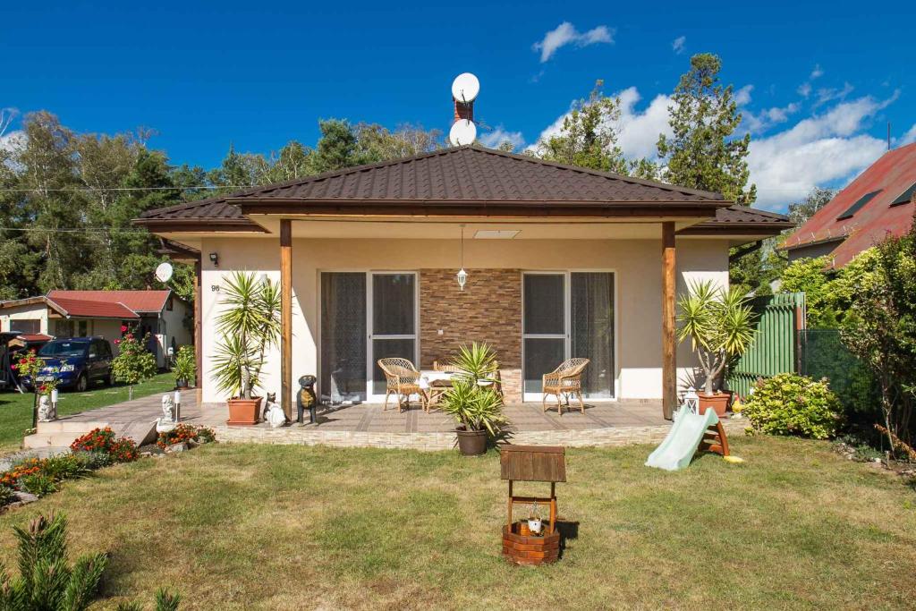 uma pequena casa com um pátio com uma mesa e cadeiras em Holiday Homes in Balatonboglar 40843 em Balatonboglár