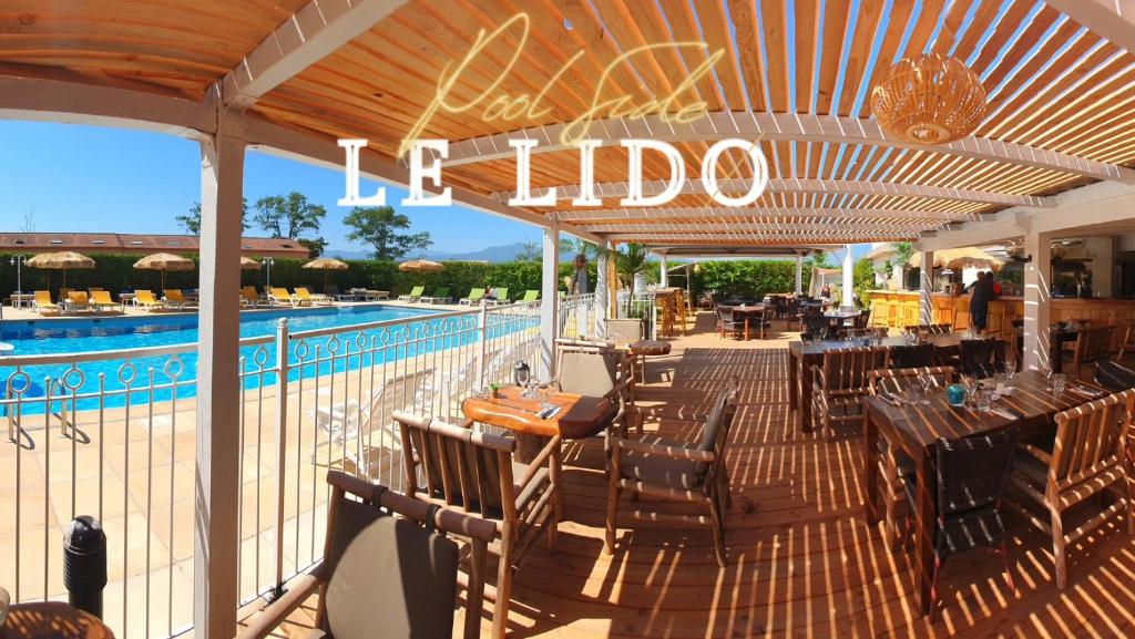 um pátio com uma mesa e cadeiras e uma piscina em Hotel Le Lido em Lucciana