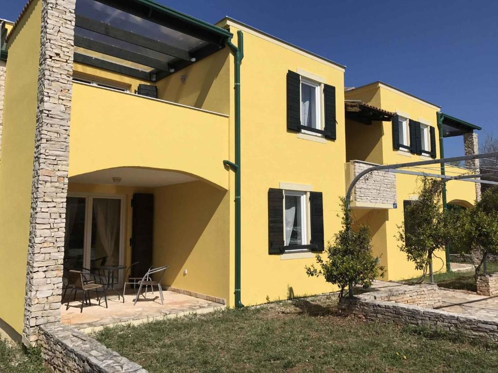 a yellow house with a table and chairs at Apartments in Umag - Istrien 26738 in Umag