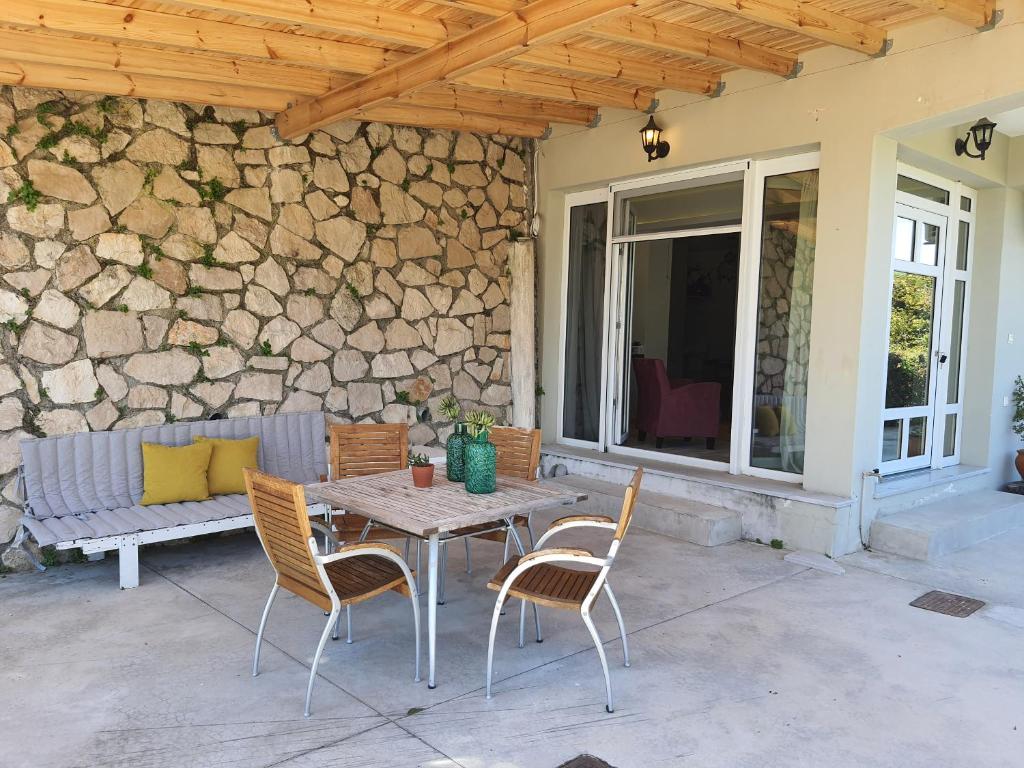 a table and chairs on a patio with a stone wall at KLADIS HOME in Akrotiri
