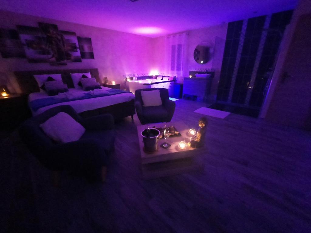 Cette chambre violette comprend un lit et un canapé. dans l'établissement Le temps d'une pause ailleurs, à Faumont