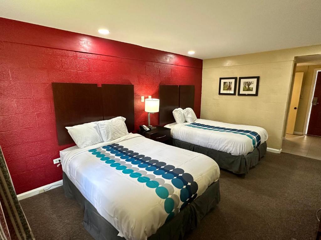 a hotel room with two beds and a red wall at Royal Inn - North Augusta - Home Of The Masters - Augusta Downtown in Beech Island