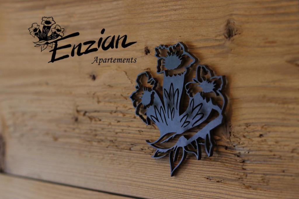 a sign on a wooden table with flowers on it at Haus Enzian Apartments in Kartitsch