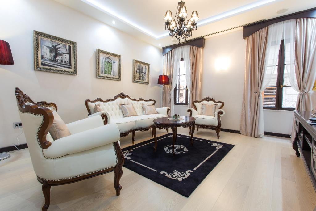 una sala de estar con muebles blancos y una lámpara de araña. en Pearl Apartments en Kotor