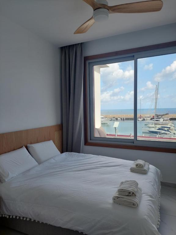 a bedroom with a bed and a window with a view of a harbor at Latchi Marina View in Polis Chrysochous