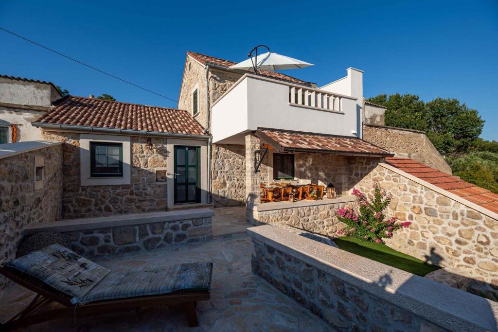 una casa in pietra con una panchina davanti di Holiday home in Ljubac - Zadar Riviera 43105 a Ljubač