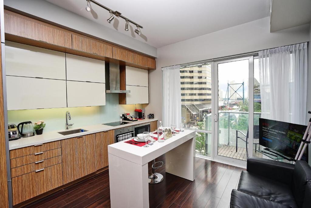 een keuken met een wit aanrecht en een groot raam bij RivetStays - Quaint 1-Bedroom Steps from CN Tower, MTCC, Union Station in Toronto