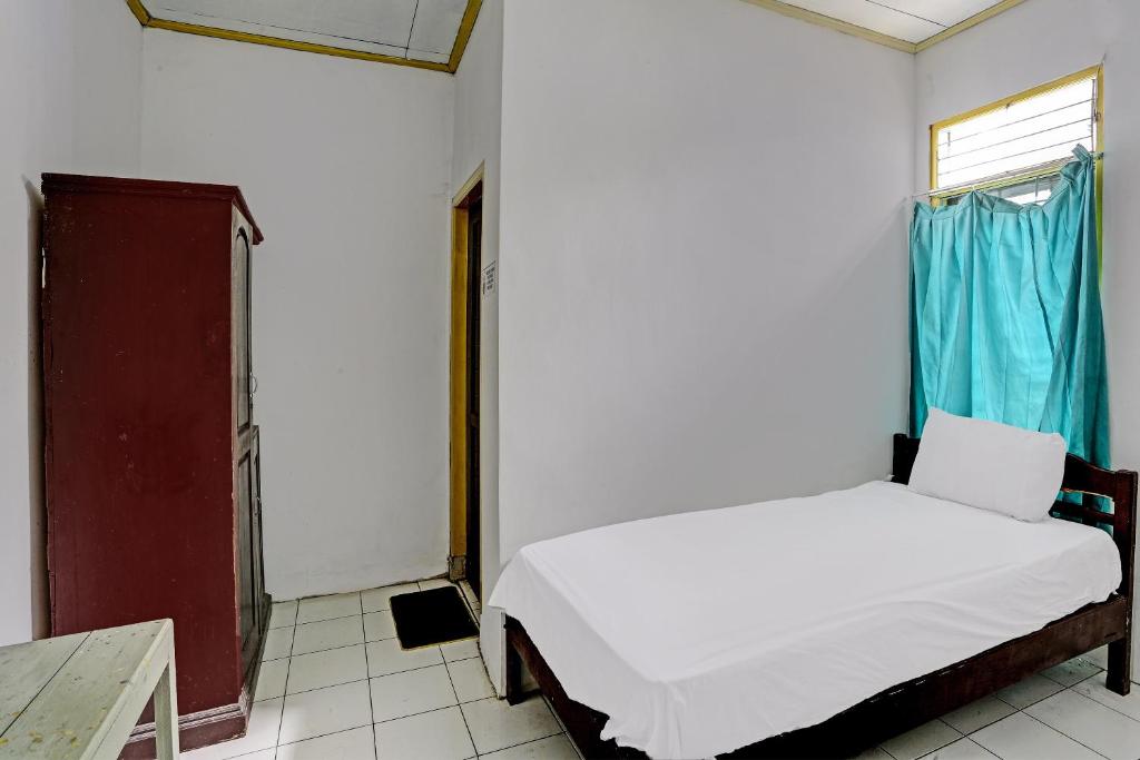ein kleines Schlafzimmer mit einem Bett und einem Fenster in der Unterkunft SPOT ON 92446 Penginapan Aina Syariah 