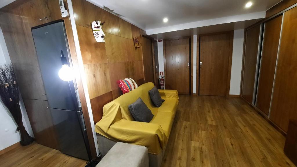 a living room with a yellow couch and wooden floors at Apimonte City House A in Bragança